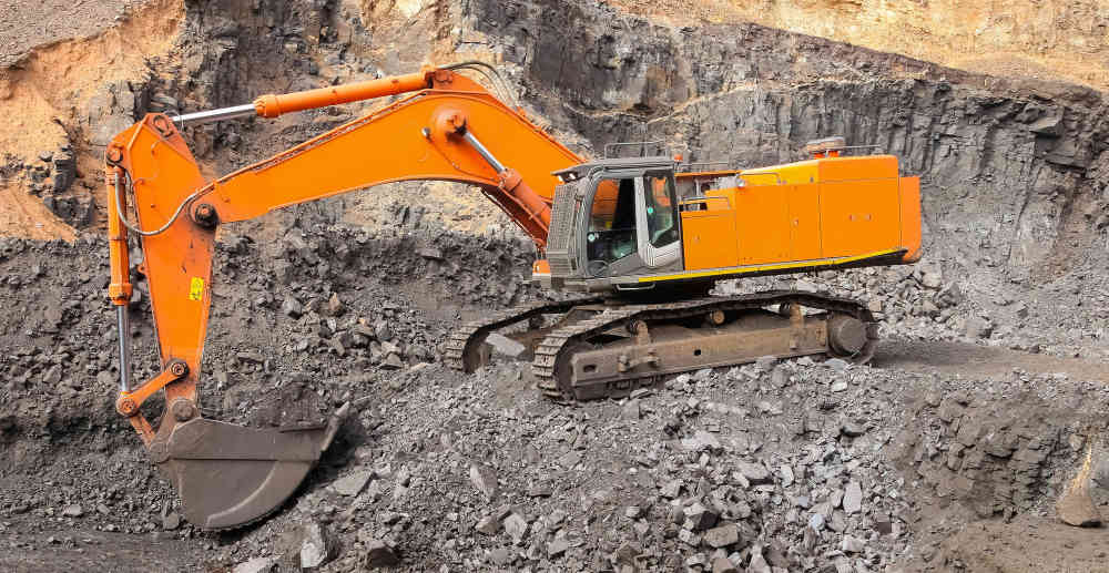 Yellow excavator digging ore-rich rock in an open-pit mine
